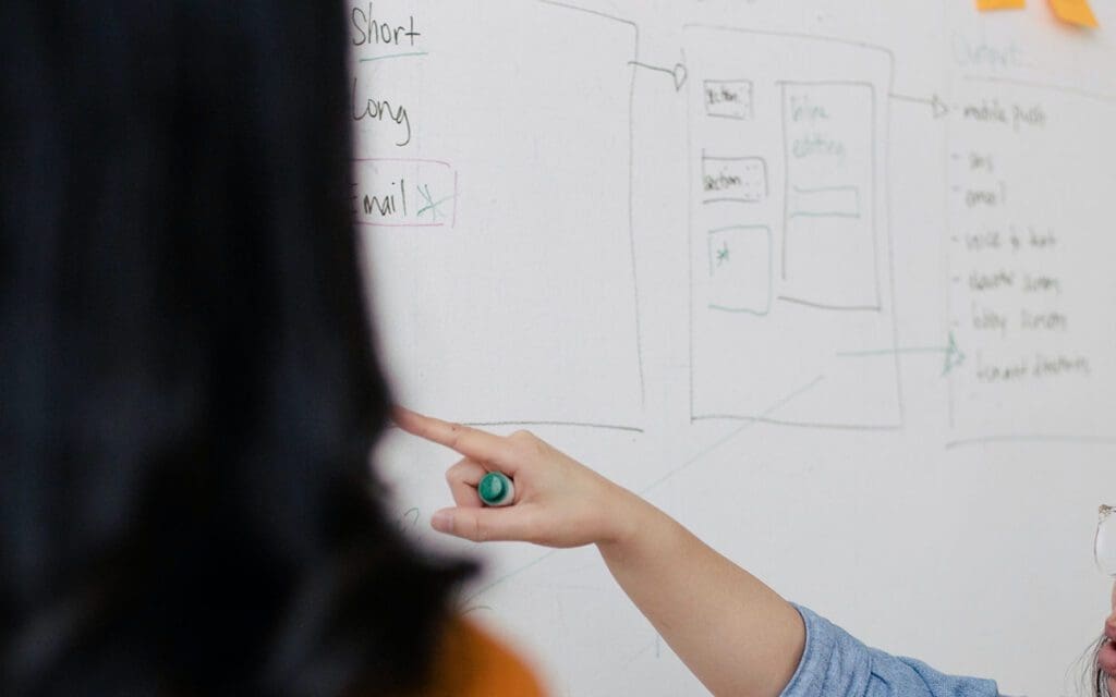 people writing on a white board