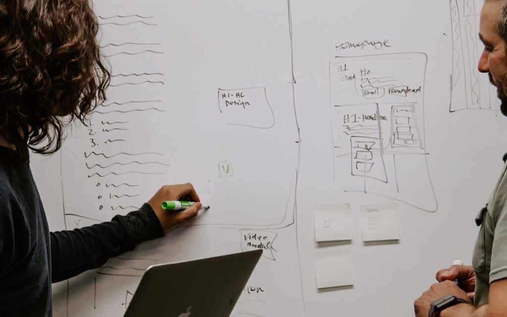 people writing on a whiteboard