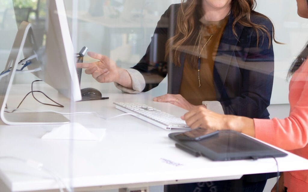 person talking to someone else pointing to a computer