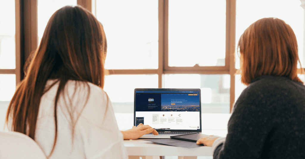 two business women looking at the inrule webiste on their computer - considering automation for their business